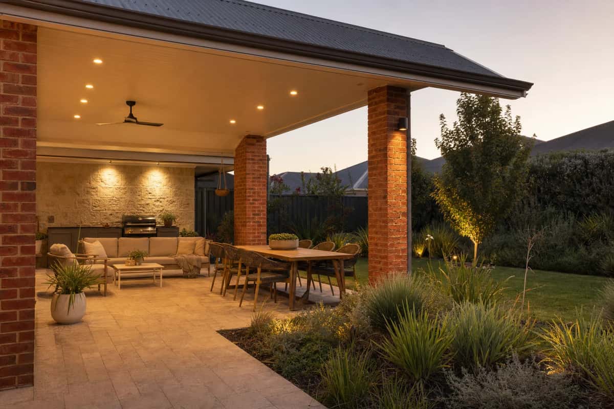 Covered alfresco at dusk with warm ceiling downlights and an outdoor lounge setting